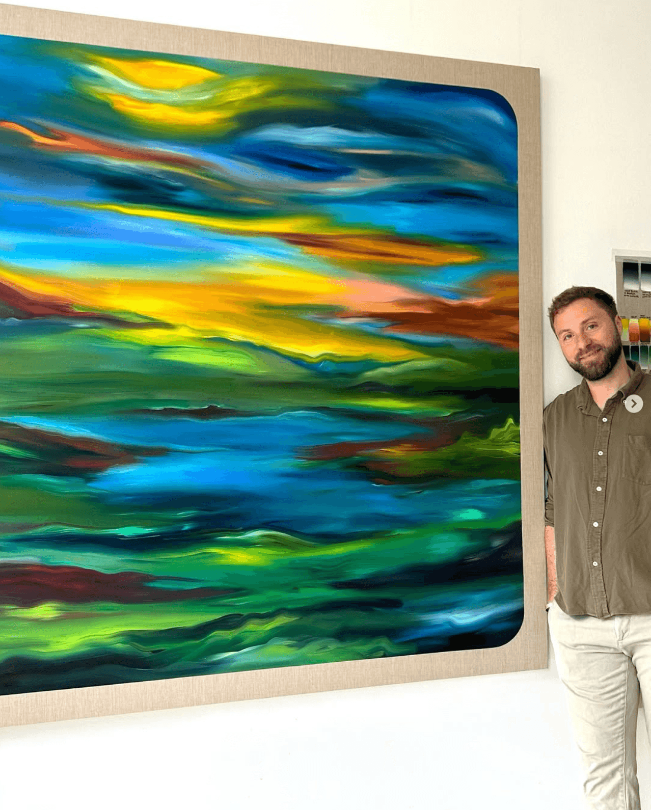Julian Potulicki standing beside one of his large paintings in the studio.
