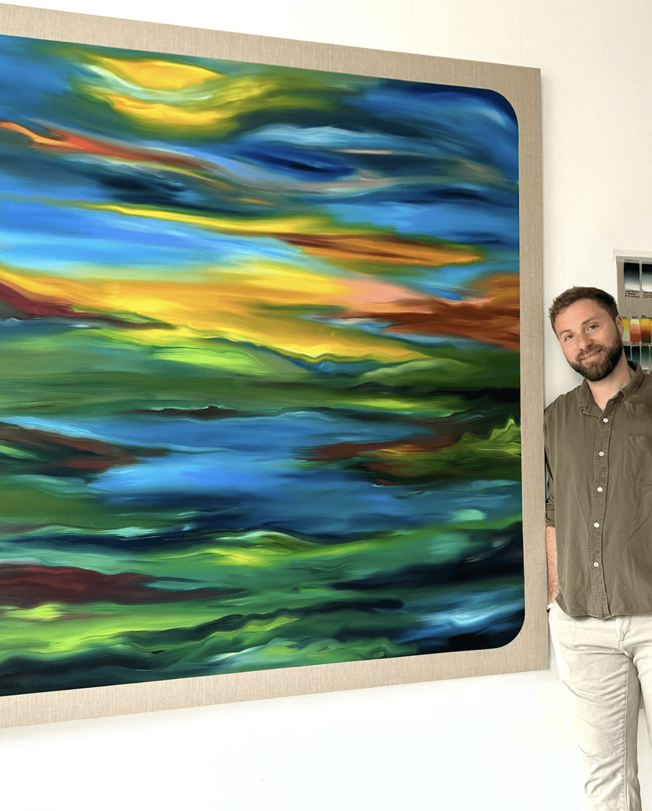 Julian Potulicki standing beside one of his waterscape paintings in the studio.