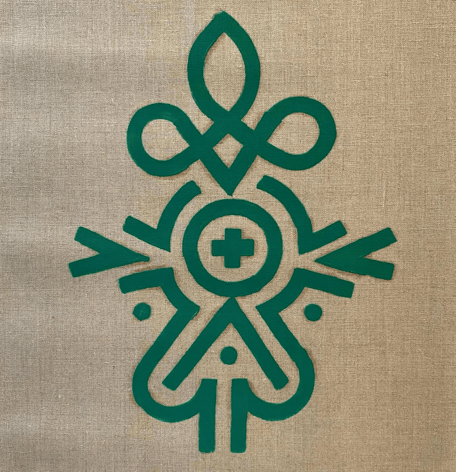 Green symmetrical figure and flower totem glyph on natural linen.