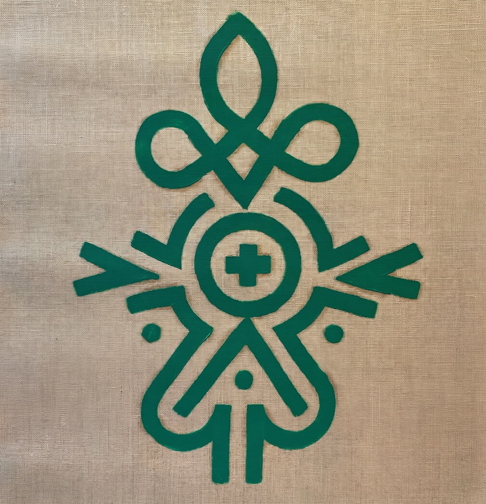 Green symmetrical figure and flower totem glyph on natural linen.