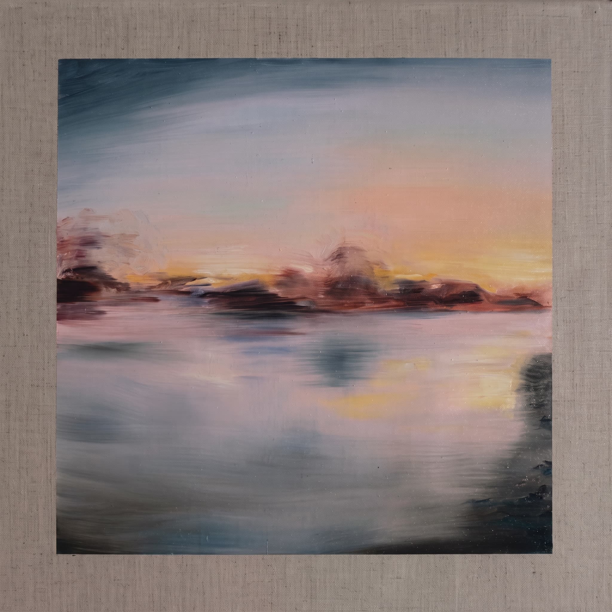Tonal muted sunset over water with a dark headland and soft reflections.