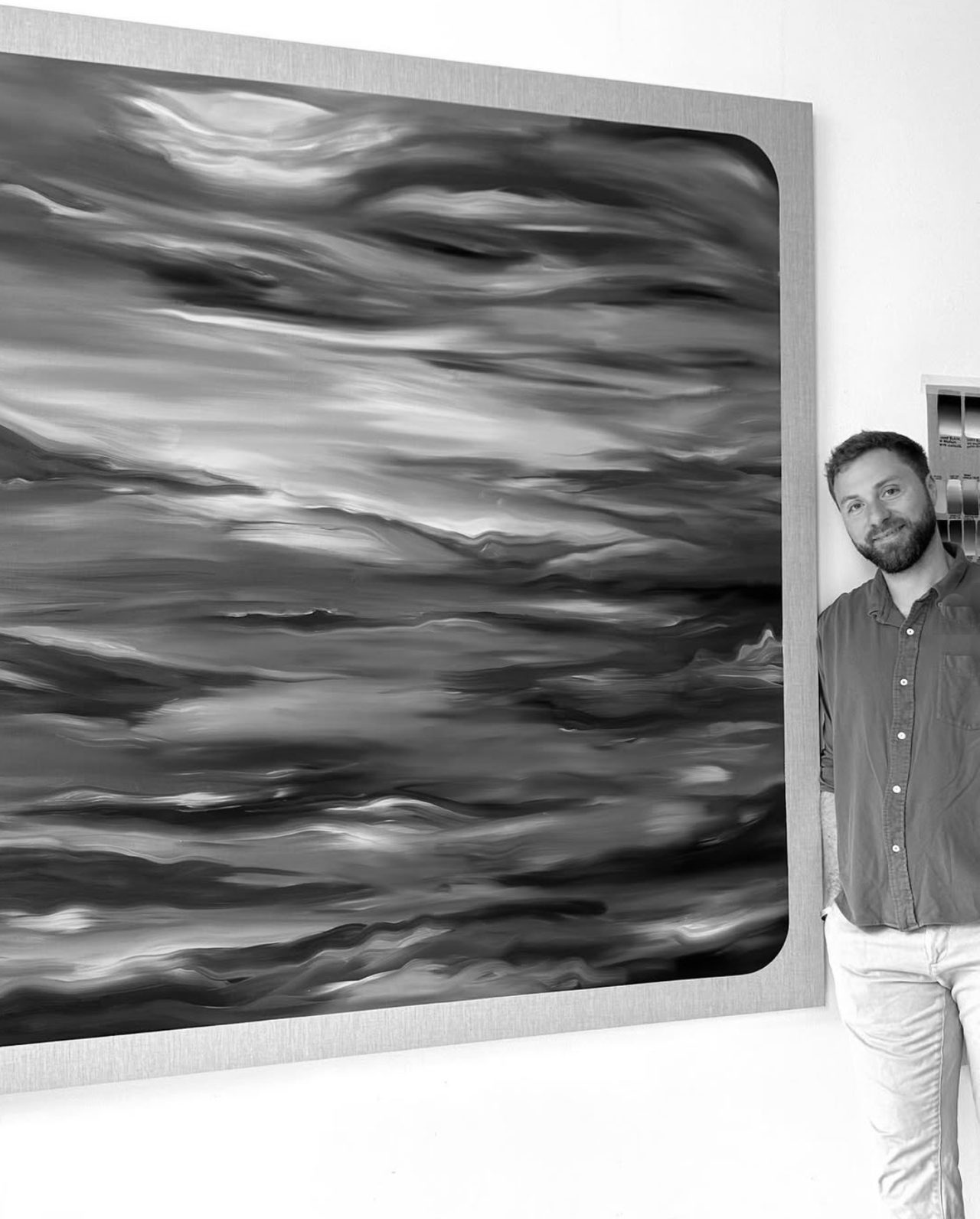 Julian Potulicki standing beside one of his waterscape paintings in the studio.